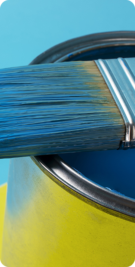 Pot de peinture bleu profond avec pinceau dessus, sur fond jaune